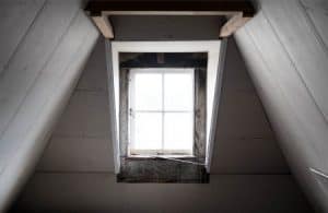 Bright natural light shining through a closed, wooden attic window