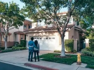 A couple standing in front of the driveway and looking at a new house