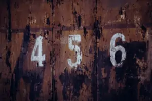 White numbers painted on old, weathered wooden fence panels