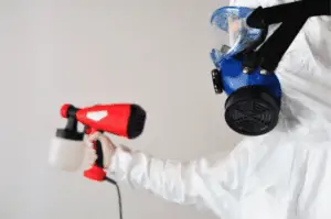 A man in protective equipment disinfecting the room.
