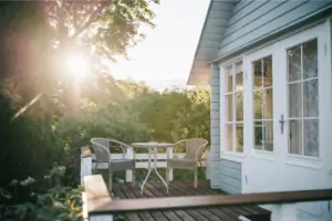 A patio on a wooden house surrounded by trees and vegetation
